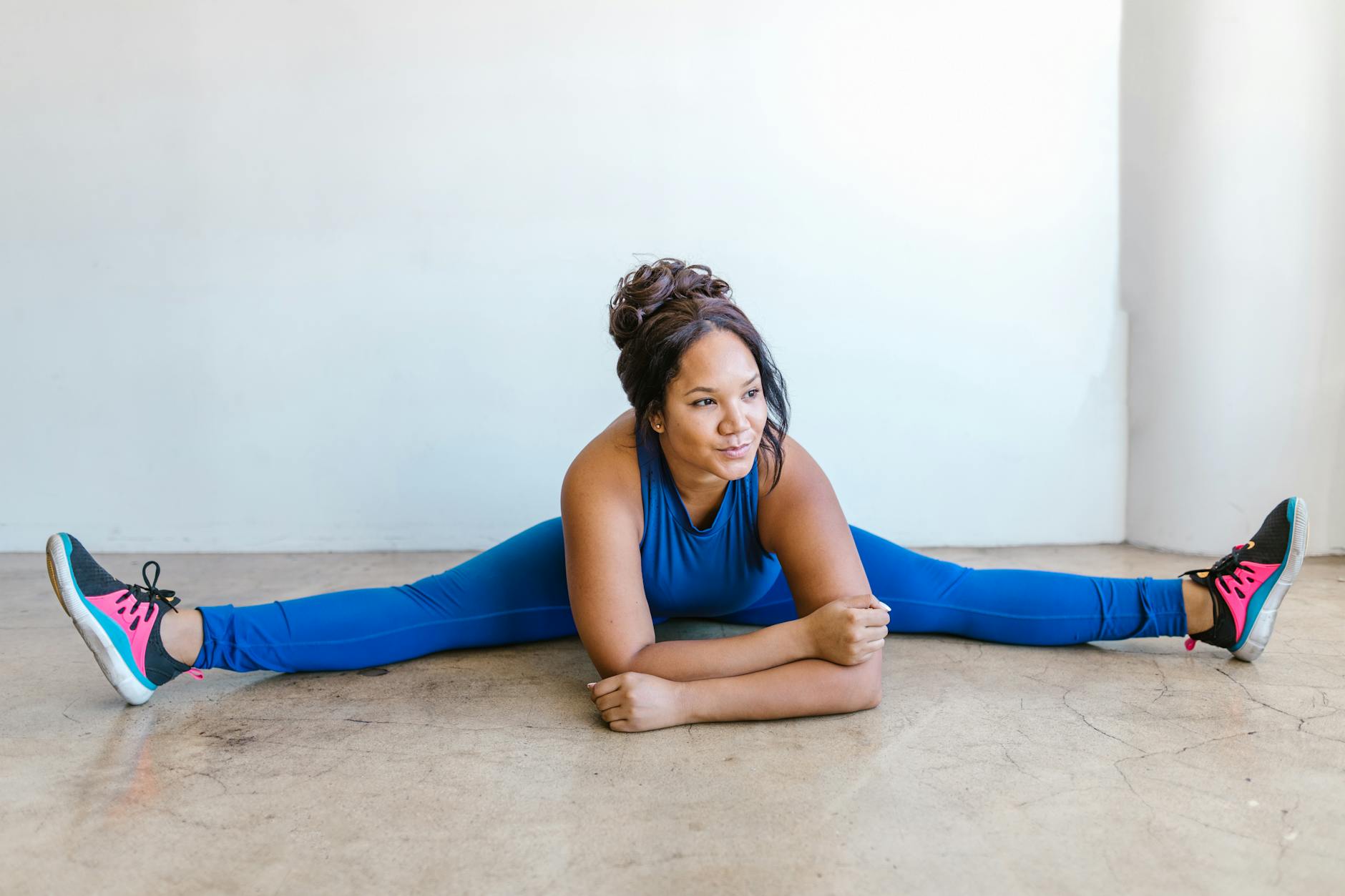 Kobieta plus size w niebieskim stroju sportowym rozciąga się na macie