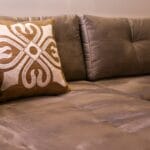 Szara elegancka sofa z dekoracyjną poduszką w nowoczesnym salonie